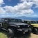 5 jeeps lined up on a grassy mountaintop near the ocean